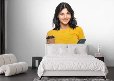 Portrait of a satisfied young woman using mobile phone while holding cup of coffee to go isolated over white background Wall mural